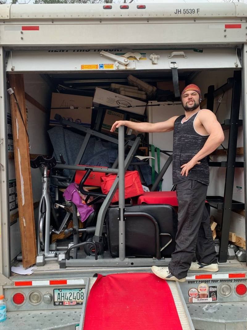 A mover standing in the back of a loaded box truck with the ramp down